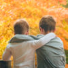 Embracing brothers sitting in autumn forest.