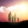 Silhouette of a family walking against a sunset sky.
