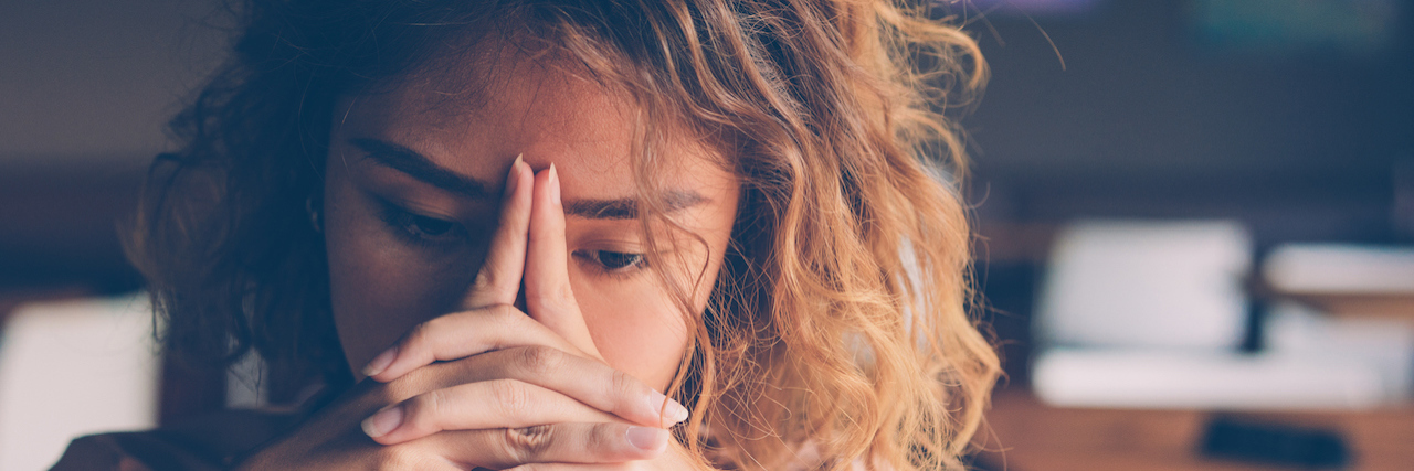 The Damage From Trauma Bonding and Intermittent Abuse Young woman leaning head on clasped hands