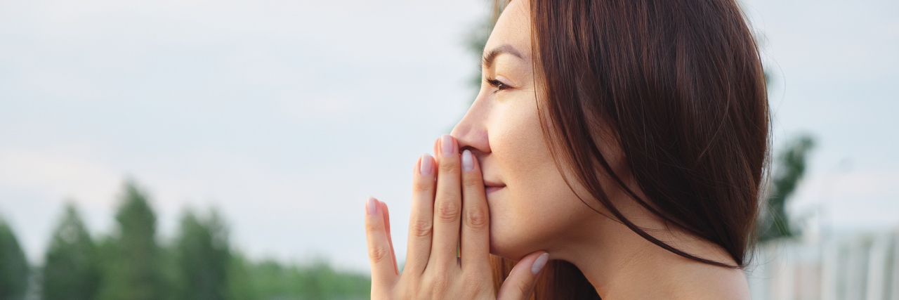 Depression Does Not Reflect a Lack of Gratitude A woman stands on a track with her hands touching her face.