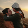 Affectionate couple on mountain at sunset.