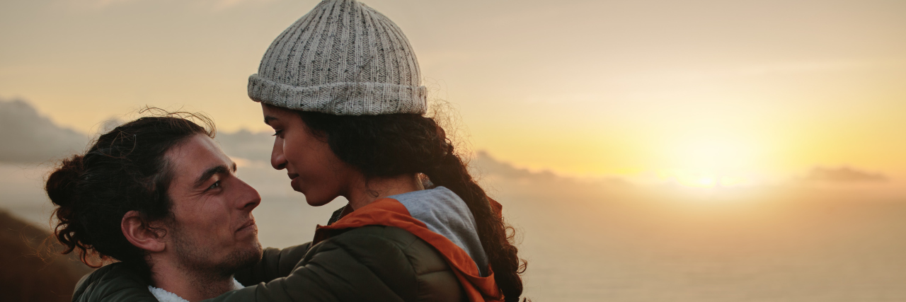 How My Spouse Supports Me in My Life With Ehlers-Danlos Syndrome Affectionate couple on mountain at sunset.