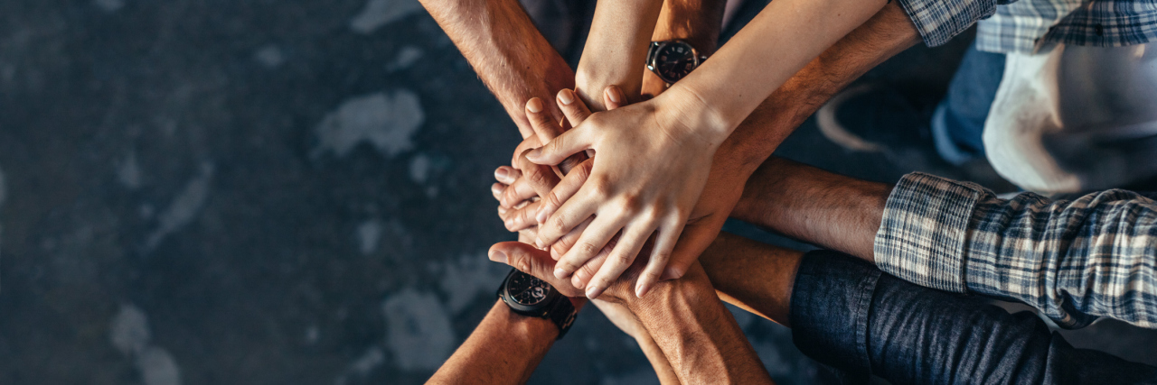How You Can Personally Help to Normalize Mental Illness A group of people with their hands in exhibiting team work.