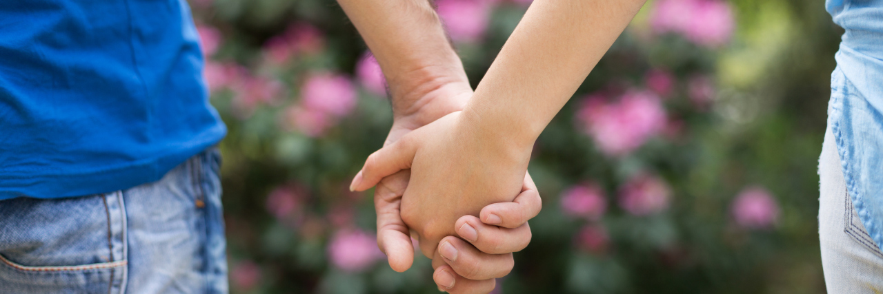 Renewed Faith In Love In Spite of Anxiety A couple stands together outdoors holding hands.