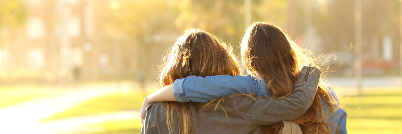 Tips for Being a Good Friend to a Trauma Survivor Back of 2 friends with their arms around each other walking during sunset