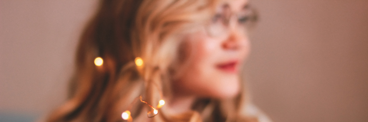 How I'm Fulfilling My Dreams While Living With Bipolar Disorder Young blonde woman in glasses with lights in her hair, blurred focus
