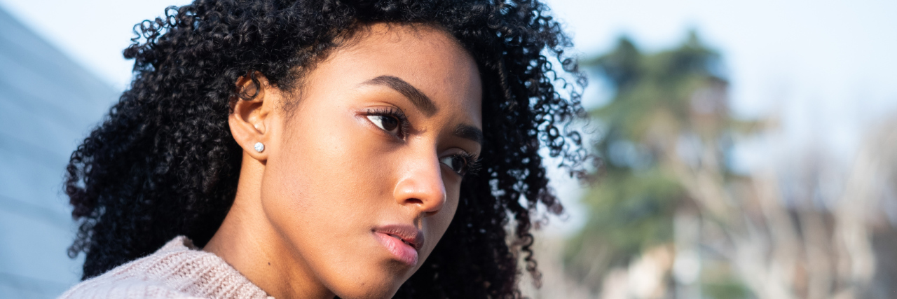 5 Types of Bullying That Are Often Overlooked in Society A woman sits alone staring off into the distance.