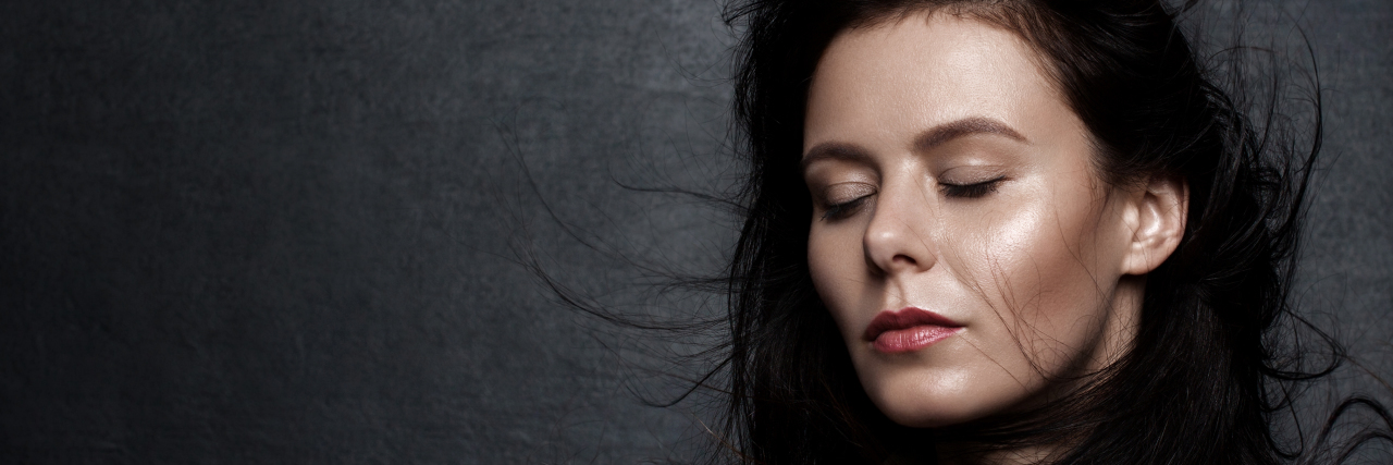 24 Things Everyone Should Know About Being in Remission A woman stands with her eyes closed in front of the camera.