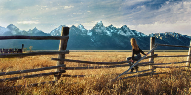 Sitting on the Fence of an Acquired Brain Injury Woman sitting on a fence looking at mountains.
