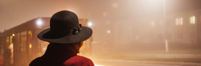 Woman waiting for the bus on a foggy night.