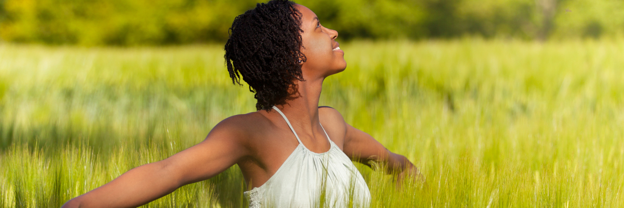 an African American woman standing and smiling in a field