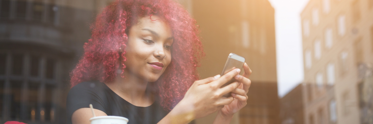 11 Apps and Websites to Help With Dyslexia Woman in a coffee shop using her smartphone.