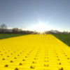 Yellow brick road on grass with sun and blue sky