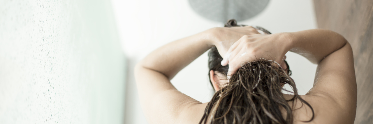 Bipolar Exhaustion Makes Showering Feel Impossible woman in the shower with long brown hair washing it