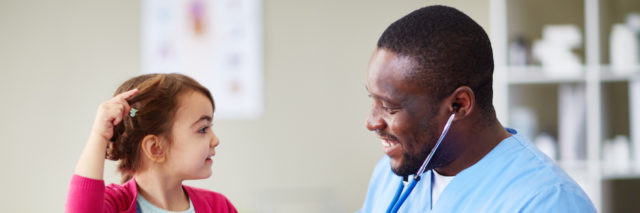 Happy male doctor communicating with child in clinic