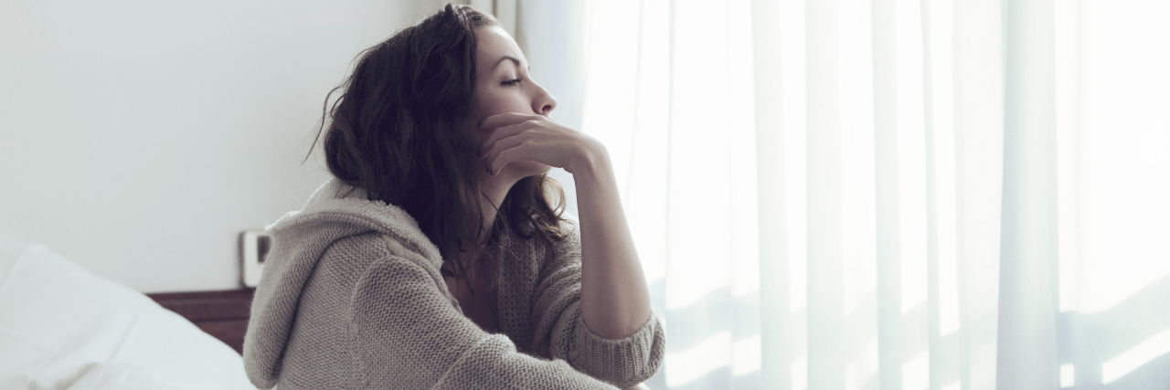 Support for Those Overwhelmed by Chronic Pain a woman sitting on a bed thinking