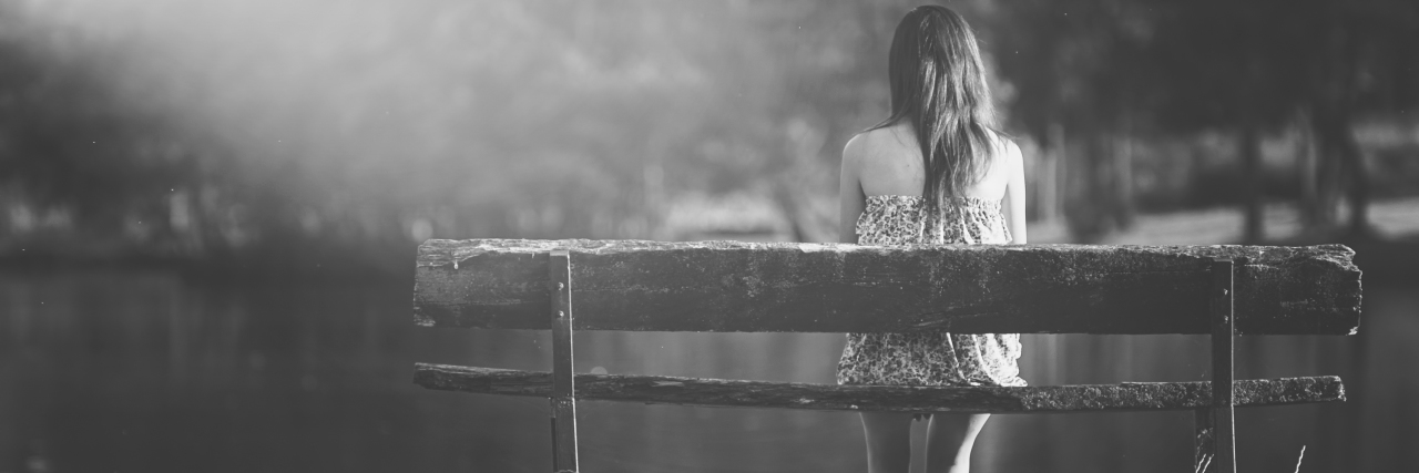 a girl sitting alone on a bench