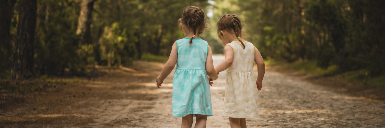 Young sisters walking down a forest road