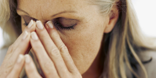 The Good, the Bad and the Ugly of Parkinson's Disease A close up of a woman with silver hair resting her head in her hands and closing her eyes