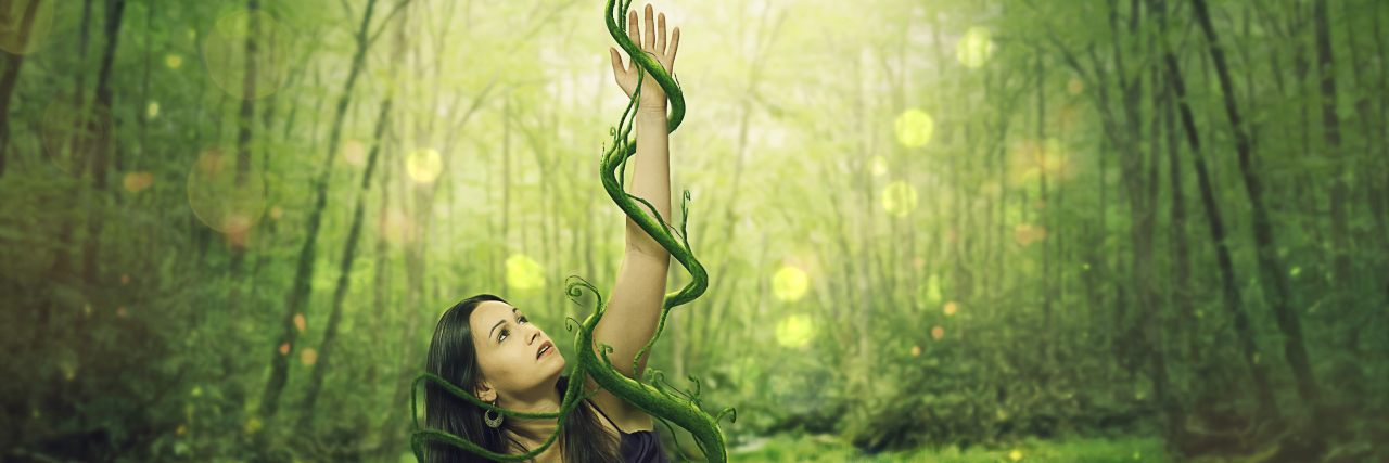 Accepting Chronic Illness Does Not Mean Defeat A woman held down by green vines as she reaches up.