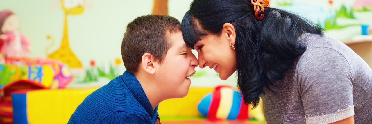 Ways To Be Positive While Parenting a Child With a Disability a mom holding hands and smiling at her son with a disability