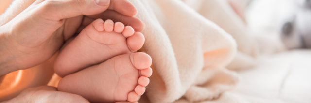 close up of woman's hands holding baby feet
