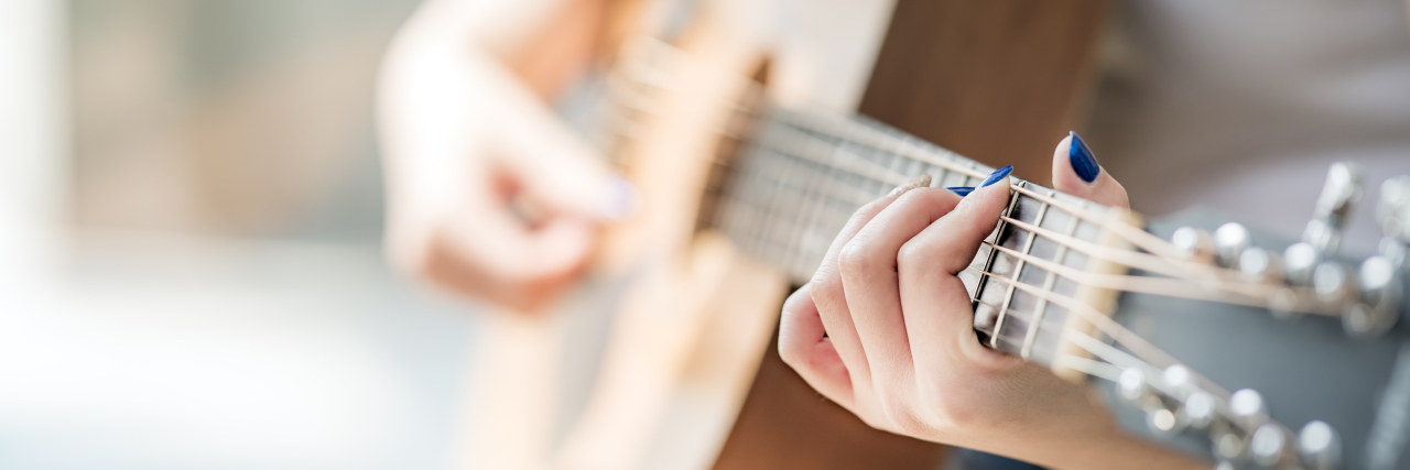 The Power of Music as a Distraction From Chronic Pain Woman playing acoustic guitar