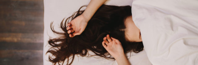 A woman lying in bed with her hair sprawled out behind her
