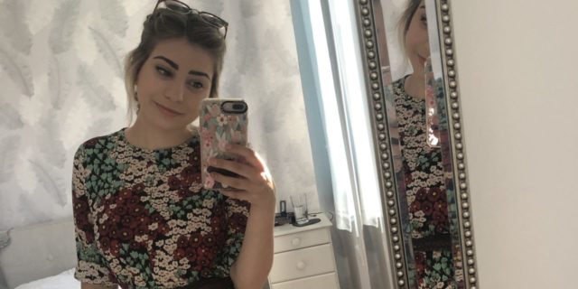 A Letter to the Body I Hate Because of My Chronic Illness A woman takes a selfie, smiling in the mirror.