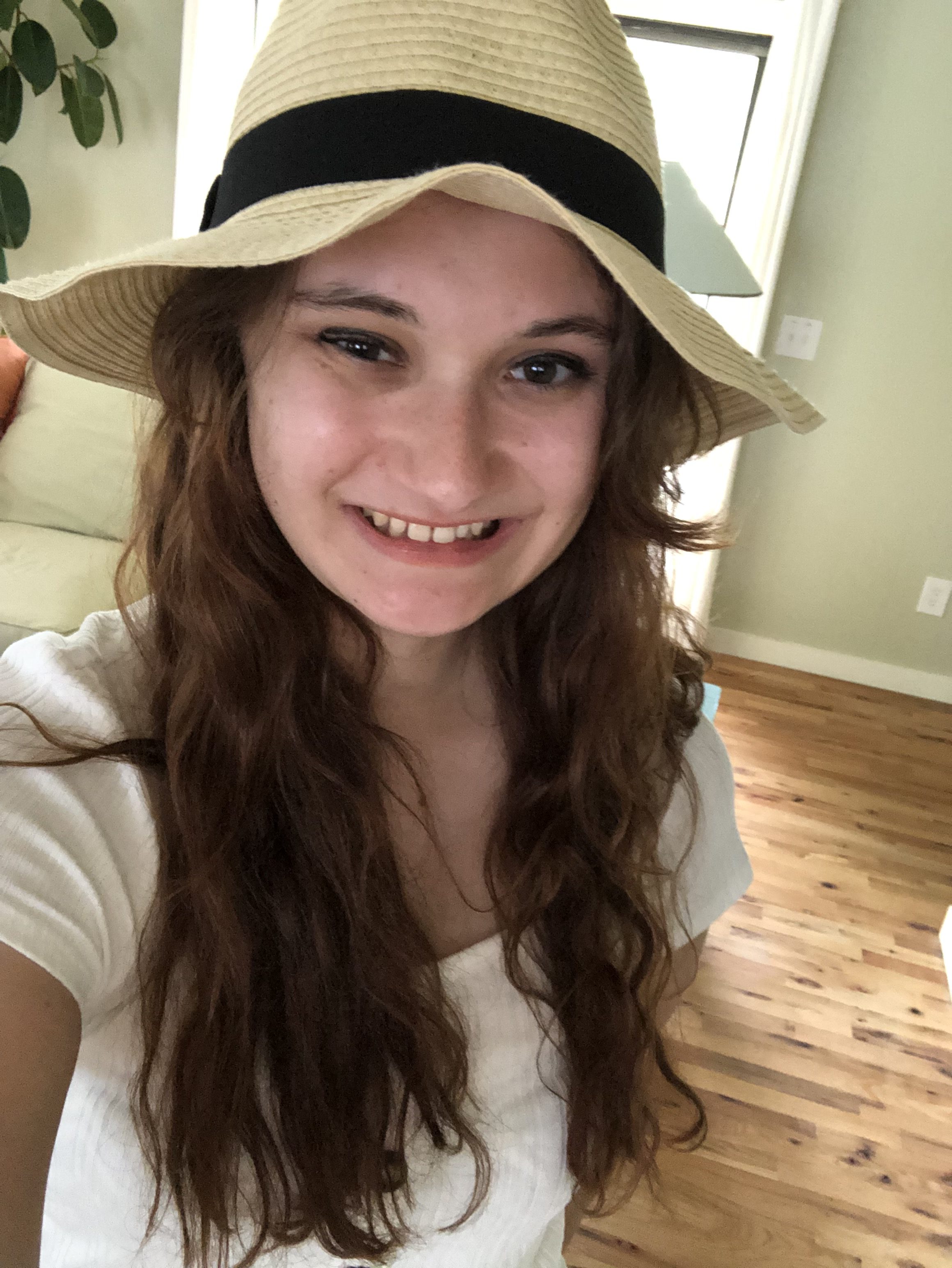 Kelly wearing a straw hat and smiling.