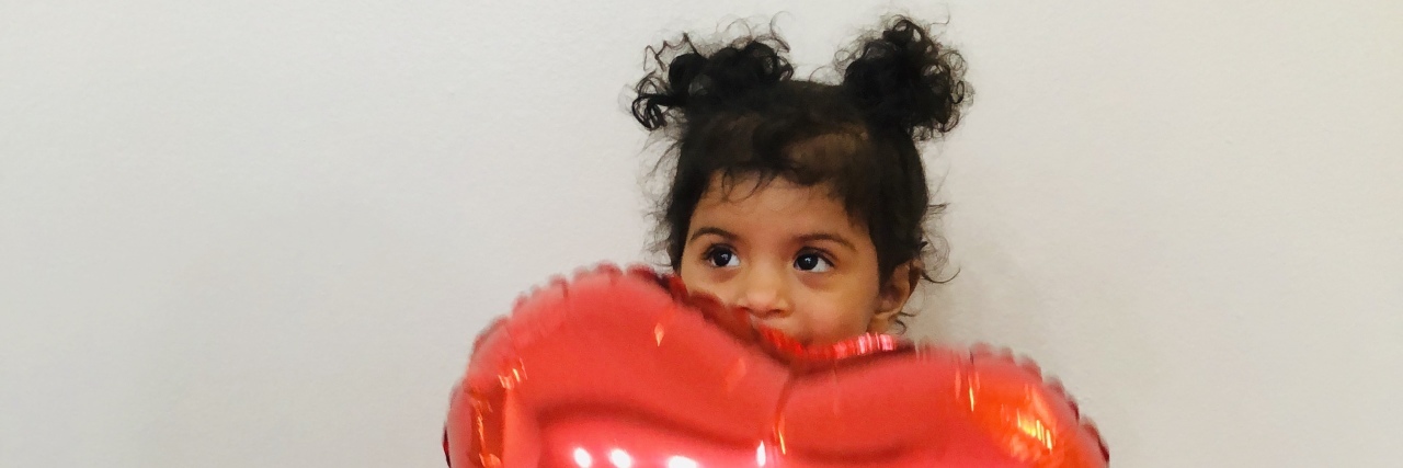 What Doctors Should Say to Parents of a Child With a Heart Defect A little girl sitting on floor and holding a red balloon