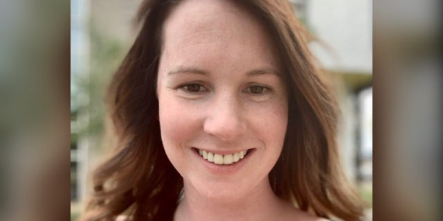 Photo of author, young woman wavy brown hair smiling in a blank tank top