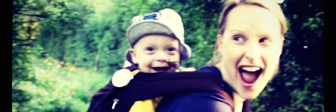 The Road to Embracing My Son's Diagnosis for What It Is a mom carrying her son on her back