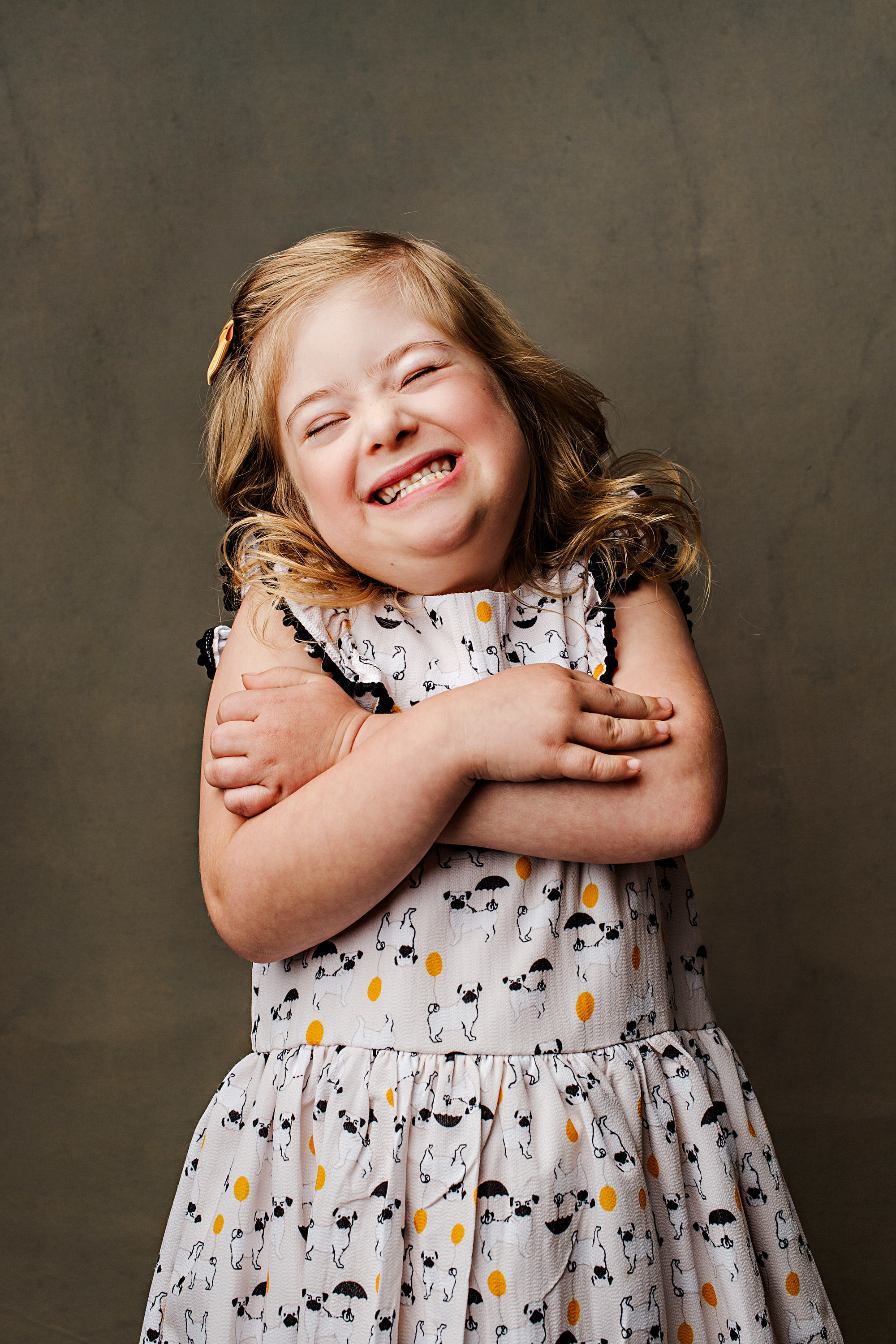 Noelle Hart, girl with Down syndrome wearing a floral dress and laughing.