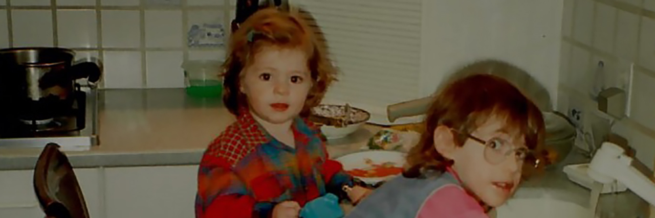Living With Cerebral Palsy After Prematurity Sarah as a child leaning against the sink washing dishes with her sister.