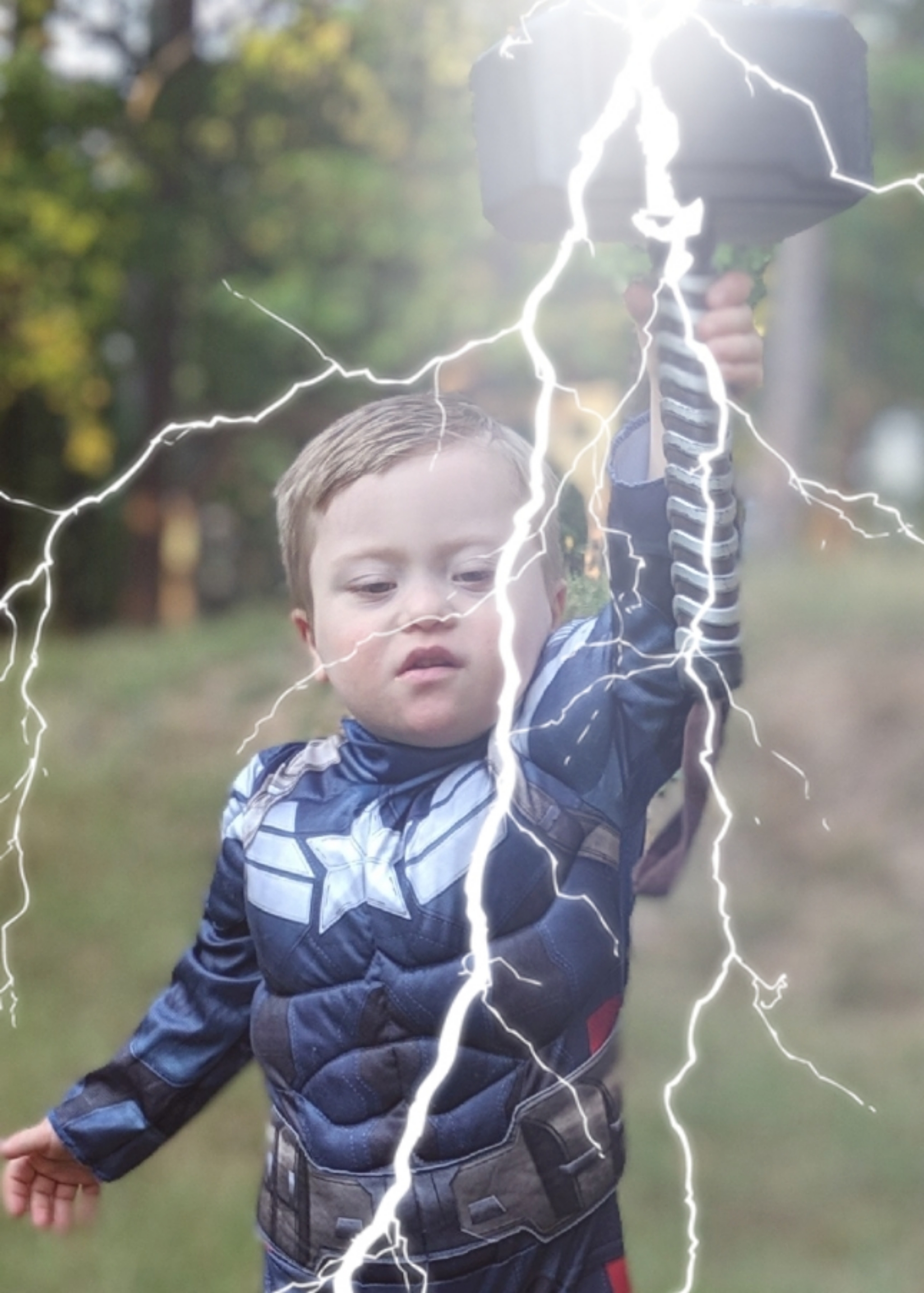 Adam's son dressed as Captain America holding Thor's hammer with lightning bolt effect..