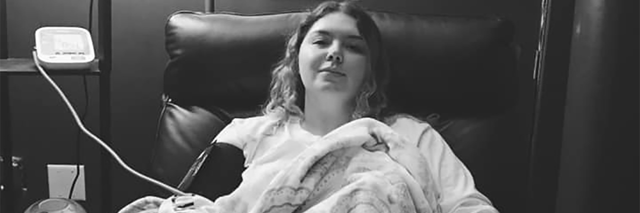 My Experience of Ketamine Treatment for Depression black and white photo of young woman in bed on hospital IV drip looking at camera. She also has a dog resting on her legs