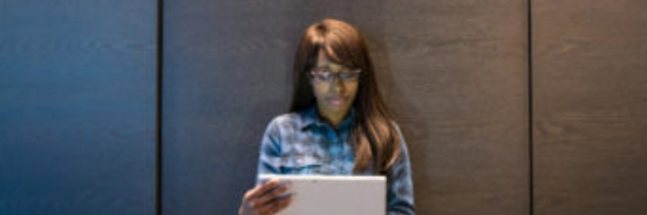 Being Bullied in the Workplace A woman sits solemnly with a laptop in hand.