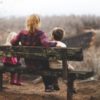 photo of woman sitting on bench between son and daughter overlooking bare trees