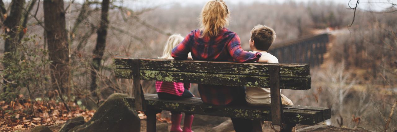 Struggling to Be a Mother With Depression and Anxiety photo of woman sitting on bench between son and daughter overlooking bare trees