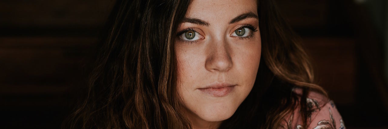 Why I Dread the Good Days With Bipolar Disorder A woman looking forward, with medium length brown hair wearing a pink shirt.
