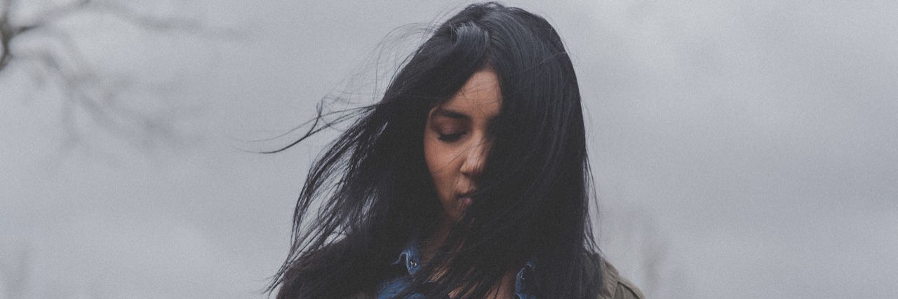 Woman standing with eyes closed an hair over her face