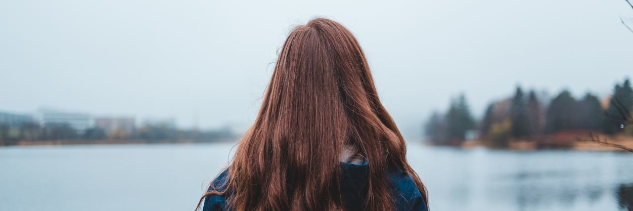 What I've Learned You Shouldn't Say to Someone With Anxiety Photo of red, wavy-haired woman with her back to the camera, looking out into a body of water