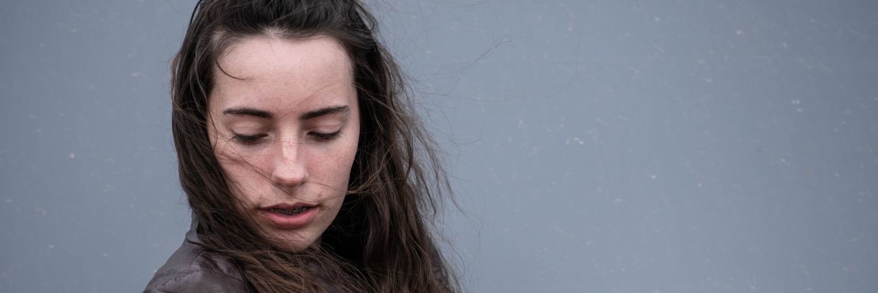 I Don't Understand Why My Depression Is Relapsing young woman with long brown hair looking down with he eyes closed and arms crossed