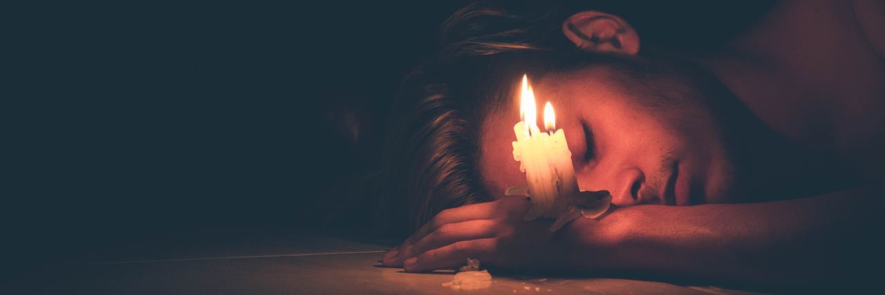 Depression, Anxiety and Leaving My Post as a Rabbi photo of man lying on floor in darkness with candle balanced on his hand