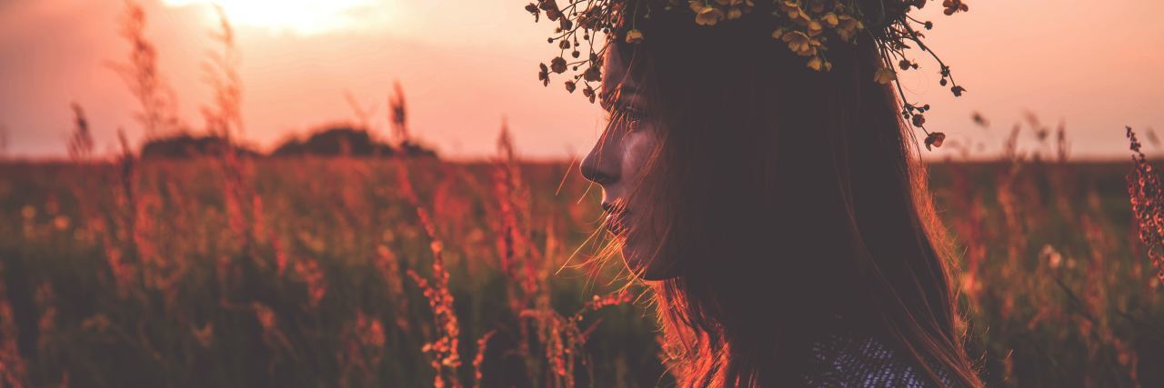 photo of young woman in a field at sunset with crown of leaves
