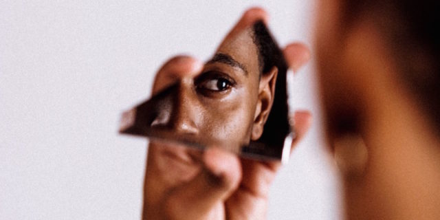 A man looking at himself in a piece of broken mirror