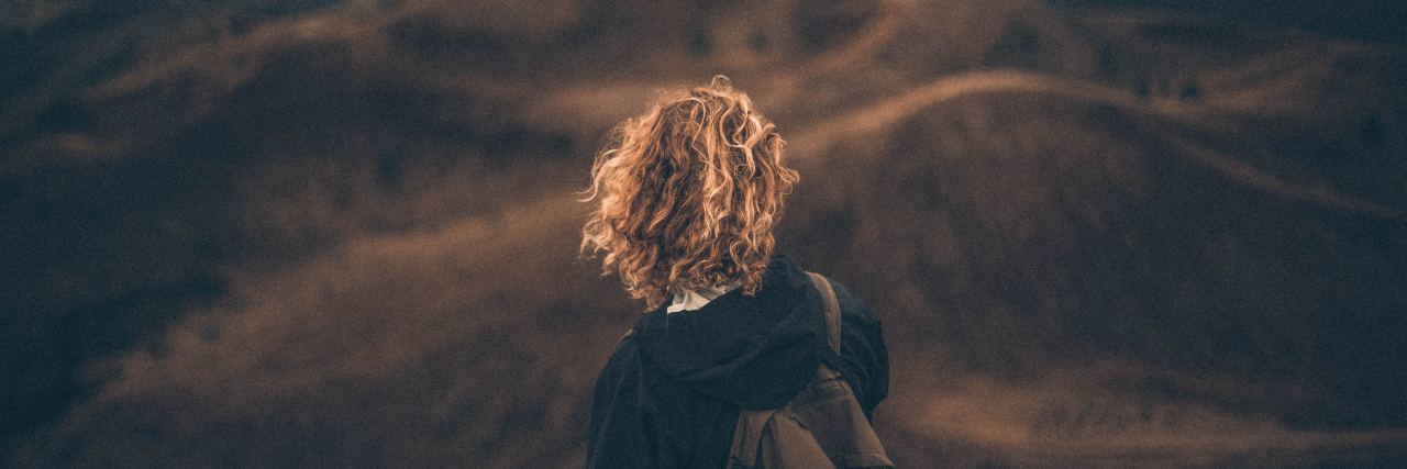 30 Mental Health Tips I've Learned Through Recovery back of a girl with curly hair and a backpack looking out into the vast mountains