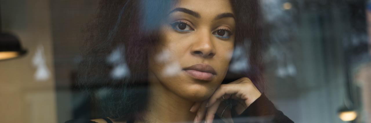 photo of woman looking into camera on other side of glass looking upset