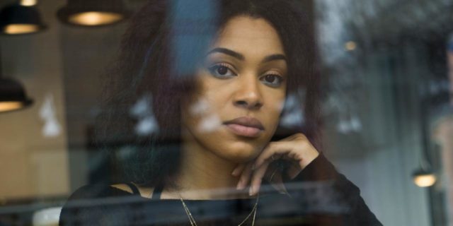 photo of woman looking into camera on other side of glass looking upset